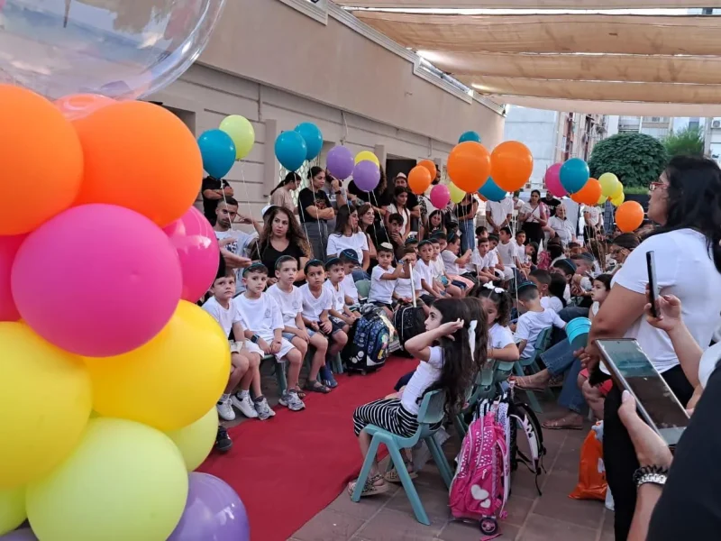 ילדים והורים בחצר מקושטת בבלונים צבעוניים באירוע חגיגי